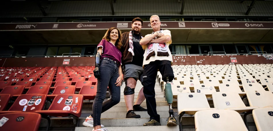 Der Personen mit unterschiedlichen Prothesen an Armen und Beinen stehen auf der Haupttribüne des Millerntor-Stadions.
