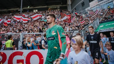 Nikola Vasilj beim Einlaufen ins Millerntor-Stadion, im Hintergrund sind Fans auf der Tribüne und weitere Spieler zu sehen.