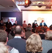 Die FCSP Fanräume von Innen. Viele Menschen stehen vor einer Bühne, während jemand eine Rede hält