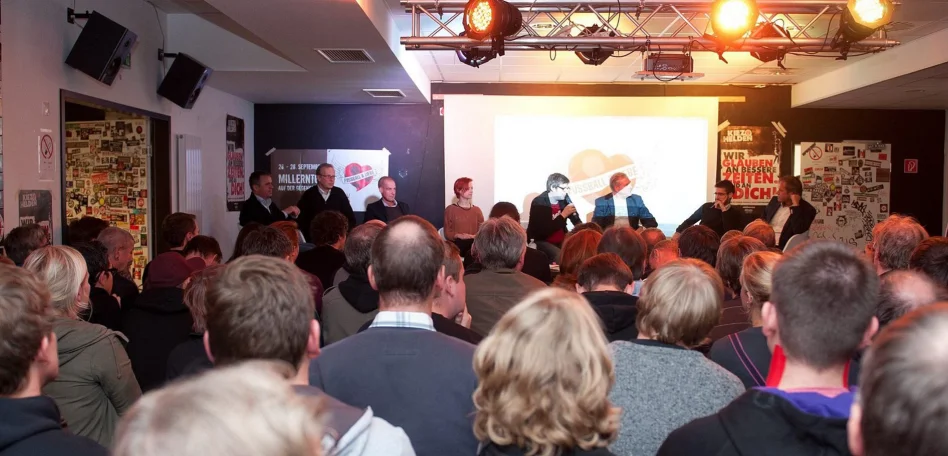 Die FCSP Fanräume von Innen. Viele Menschen stehen vor einer Bühne, während jemand eine Rede hält