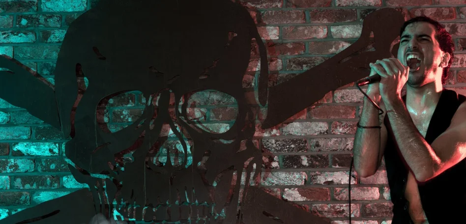 Ein Sänger singt auf der Bühne vor einem großen, schwarzen Totenkopf