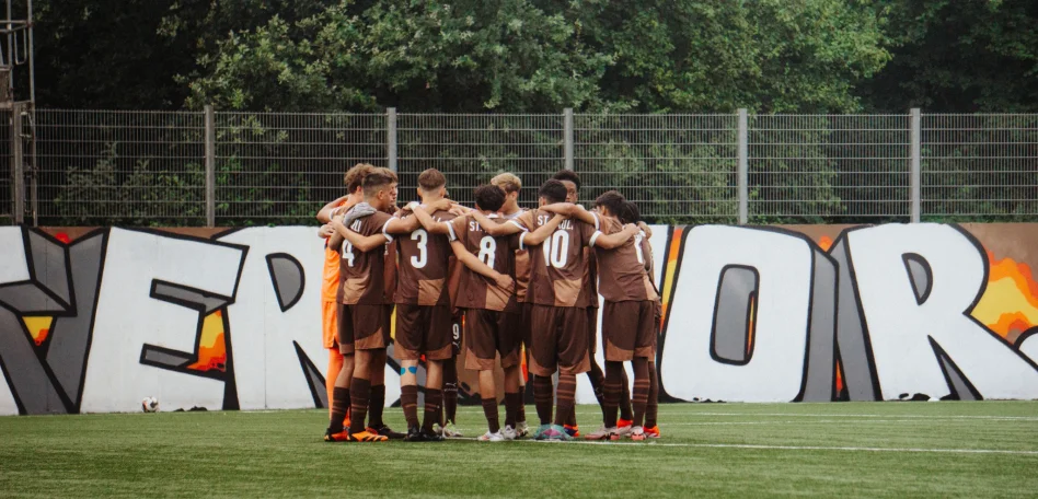 Das Bild zeigt ein Team des FC St. Pauli Nachwuchsbereichs im Kreis stehend.