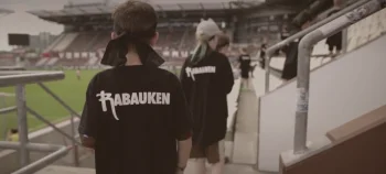 Rabauken sind im Millerntor-Stadion. Man sieht sie von hinten, sie tragen ein Rabauken-Tshirt.