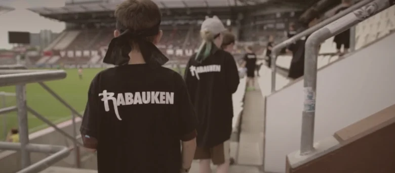 Rabauken sind im Millerntor-Stadion. Man sieht sie von hinten, sie tragen ein Rabauken-Tshirt.