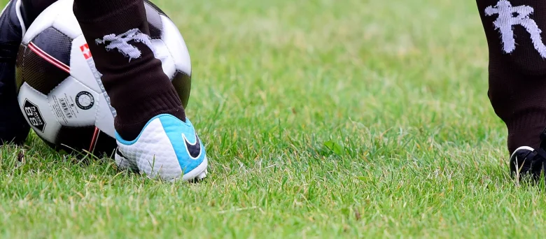 Füße einer Person, die einen Fußball kicken