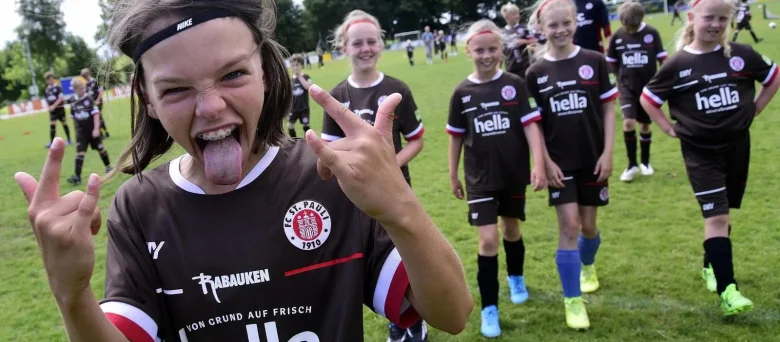 Rabauken am Spielfeld. Ein Kind grinst frech in die Kamera.