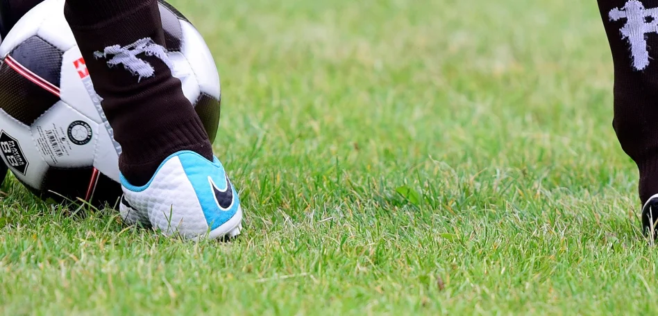 Füße einer Person, die einen Fußball kicken