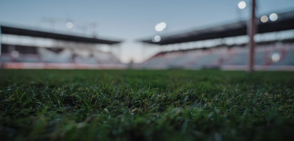 Man sieht das Millerntor Stadion von innen, unscharf durch den Rasen fotografiert.