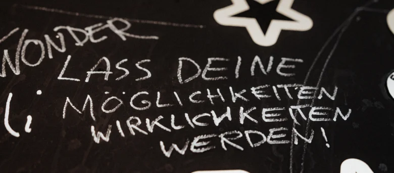 Eine schwarze Fläche mit dem Schriftzug "Lass deine Möglichkeiten Wirklichkeit werden"