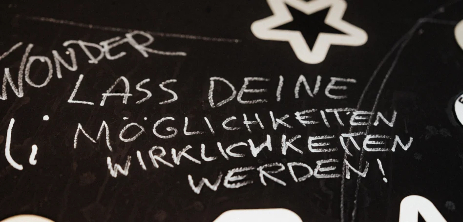 Eine schwarze Fläche mit dem Schriftzug "Lass deine Möglichkeiten Wirklichkeit werden"
